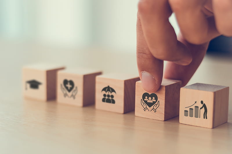 A set of block with icons of benefits on them and a hand grabbing one of them